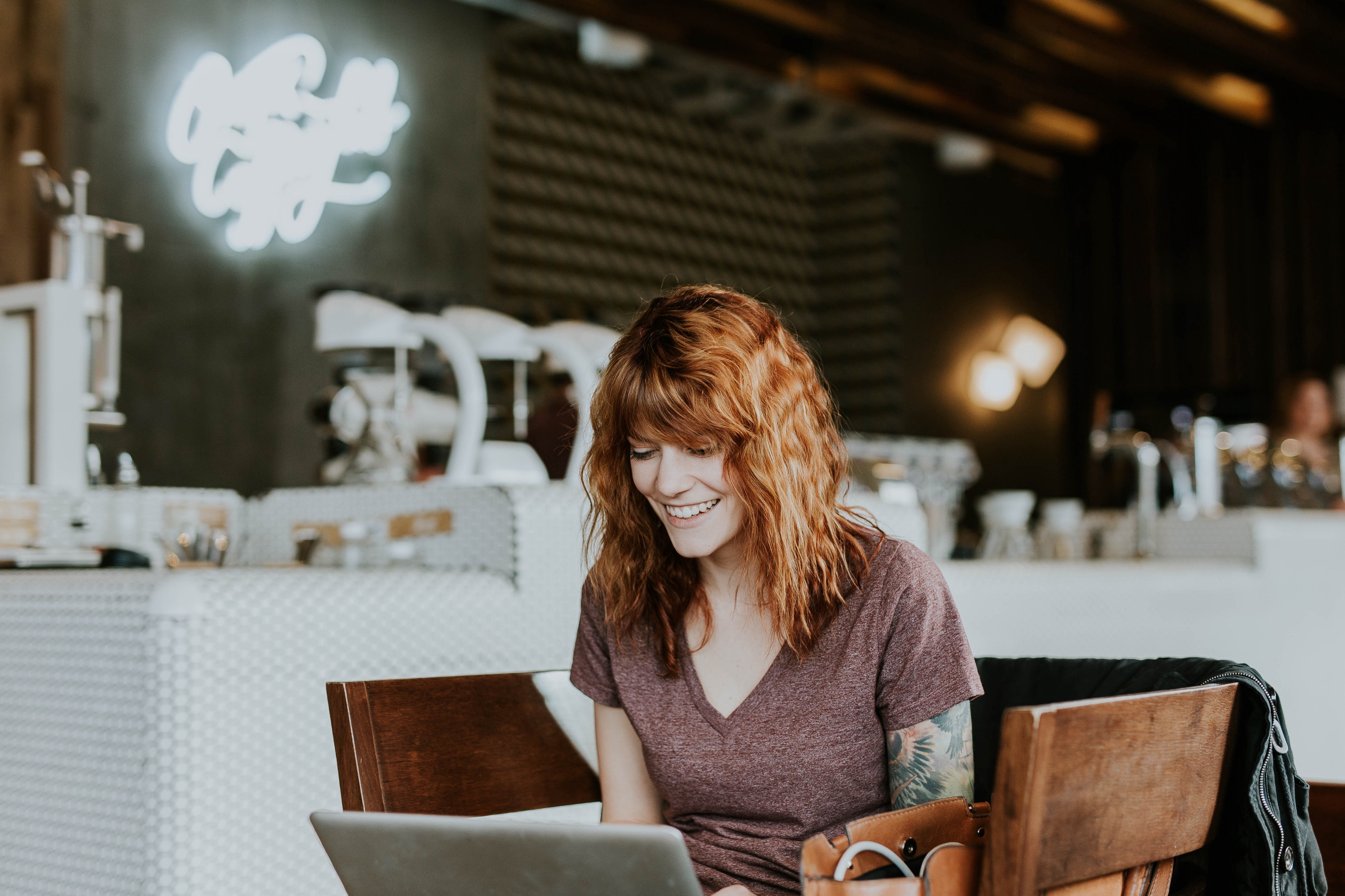 smiling woman in cafe with laptop on her laptop